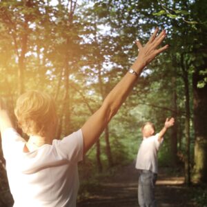 Frau und Mann praktizieren Achtsamkeitsmeditation zur Stressbewältigung und Resilienzsteigerung in der Natur und im Kloster