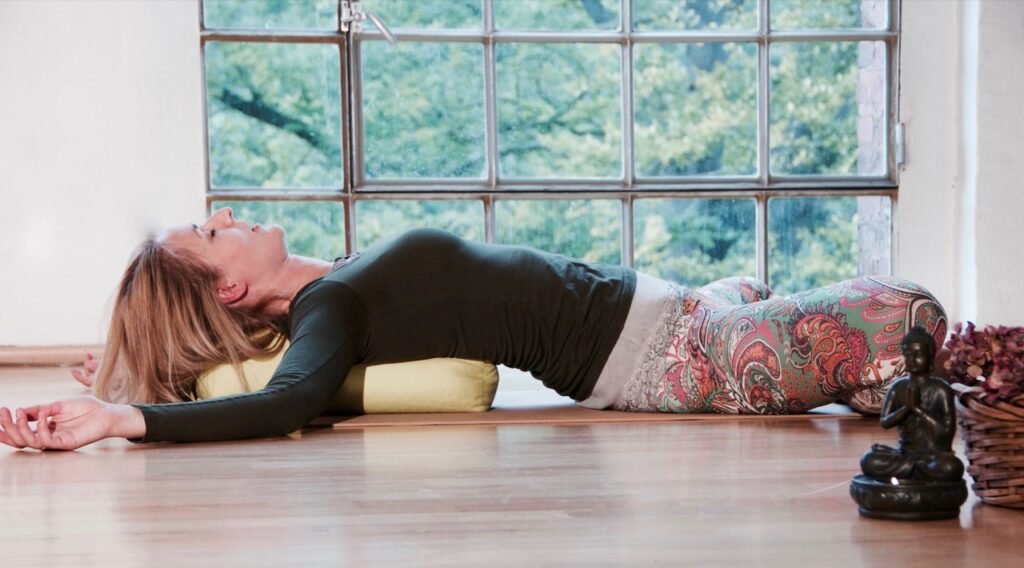 Frau bei einer regenerierenden Yin Yoga Übung während eines Slow Yoga Retreats. Sanfte Bewegungen und Meditation fördern Entspannung und Stressabbau - Auszeit im Kloster.