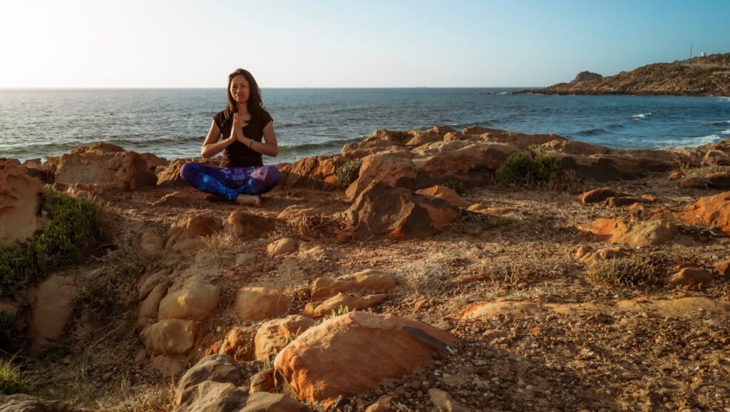 Frau beim Soul slow & Yin Yoga Retreat an der Ostsee bei Sonnenaufgang beim meditieren